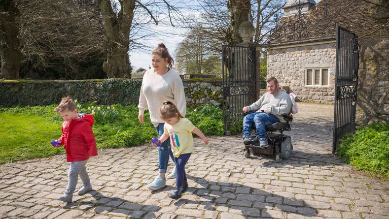Two adults and two children make their way through the gate at Avebury, Wiltshire